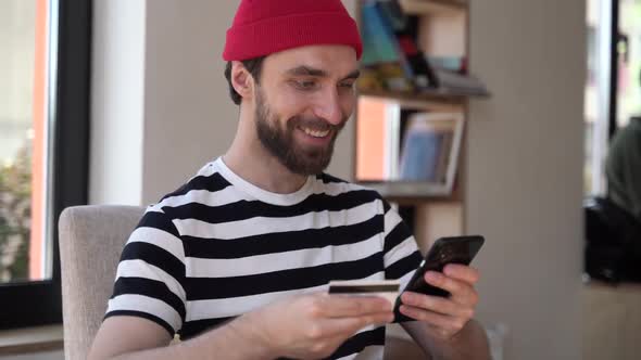 Smiling, positive guy with a beard is shopping online alt