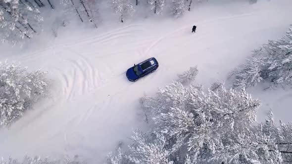 Aerial view of a car driving in the snowy forest in Estonia. alt