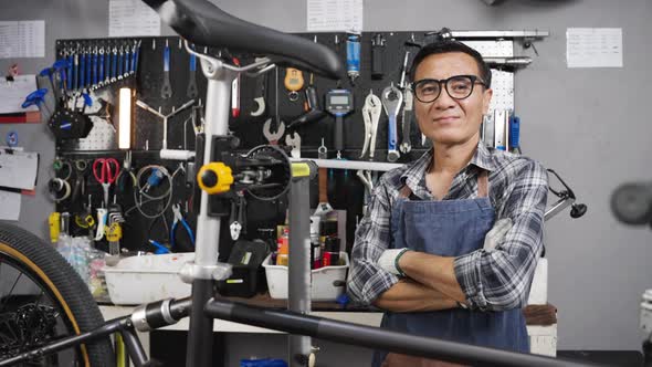 Portrait shot of Asian senior man owner bicycle shop smiling and looking at camera