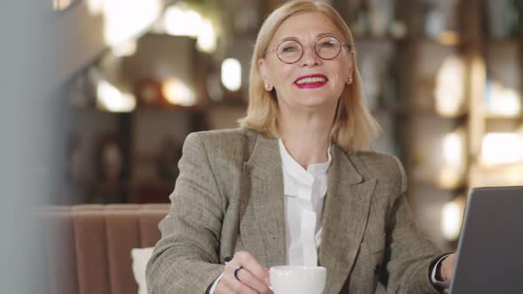 Portrait of Smiling Senior Businesswoman with Laptop in Restaurant alt