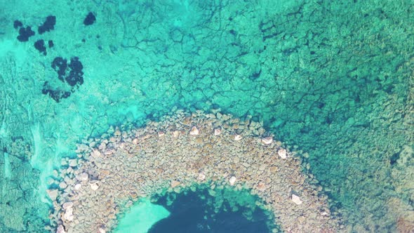 A beautiful stone path is visible through the turquoise clear sea water. Top view,
