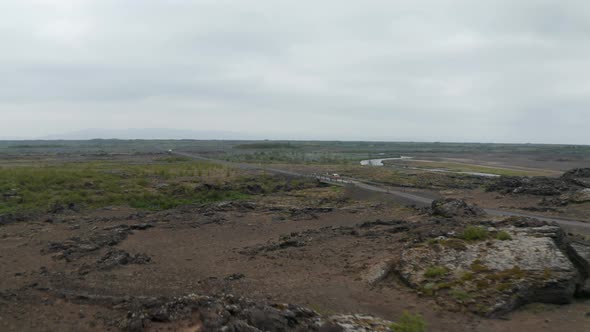 Birds Eye View of Rocky Highlands in Iceland with River Flowing Under Bridge alt