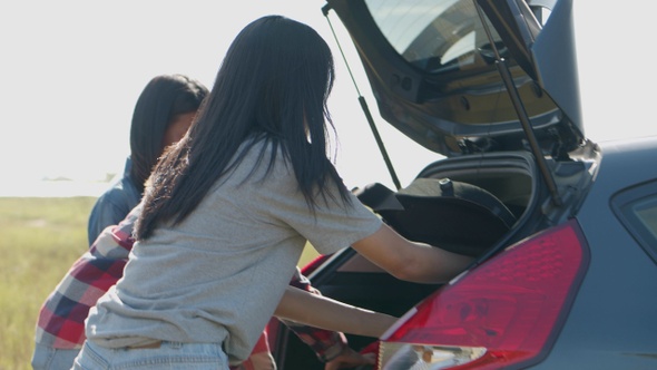 A group of young teen Asian women opens the back door of the car with friends camping.