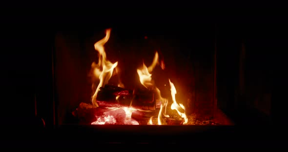 Hot Fire of Burning Wood in Glass Fireplace in Dark Room at Night