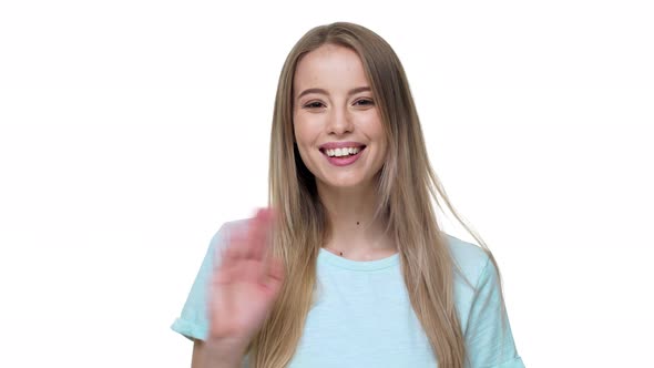 Portrait of Hospitable Blond Woman with Long Hair Smiling on Camera and Greeting with Waving Hand alt