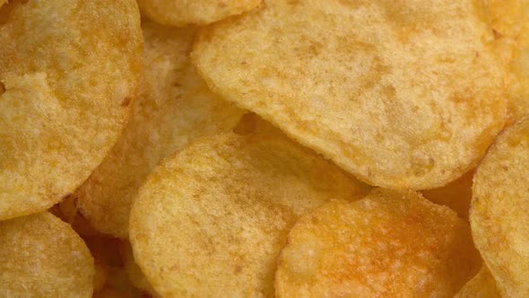 Crispy potato chips rotating in macro. Golden fried potatoes close up. Potato snack for unhealthy alt