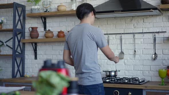 Back View of Young Asian Man Mixing Food in Pan in Slow Motion alt