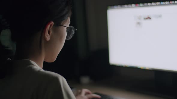 Asian female wearing glasses using computer.