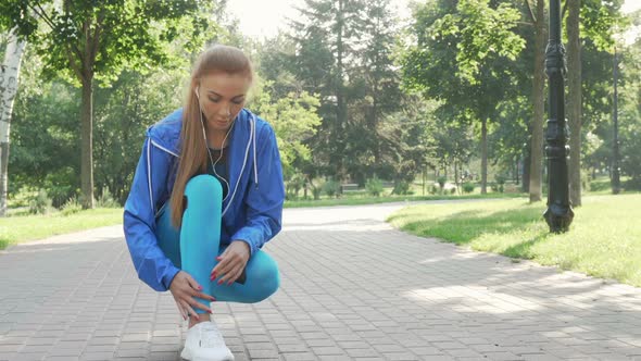 Beautiful Sportswoman Tying Her Shoelaces Before Running in the Park