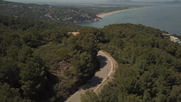 Flying above a young man skateboarding on a road near the sea