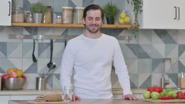 Young Man Smiling at the Camera While Standing in Kitchen alt