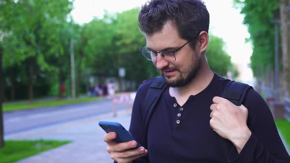Handsome Man in Glasses Using Smartphone on the Street alt