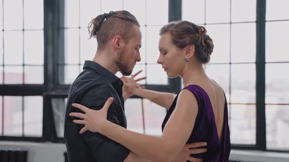 Close Shot of Couple Dancing Tango in Grey Studio Against Large Windows