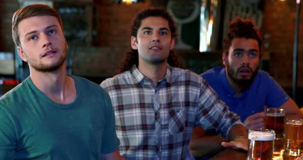 Friends cheering while having beer at bar counter alt