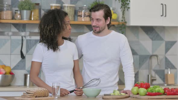 Mixed Race Couple Talking While Standing in Kitchen alt
