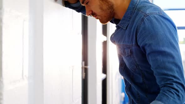 Tired businessman leaning on wall alt