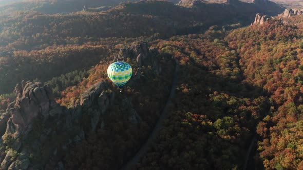 Hot air balloon flying over picturesque rock formation alt