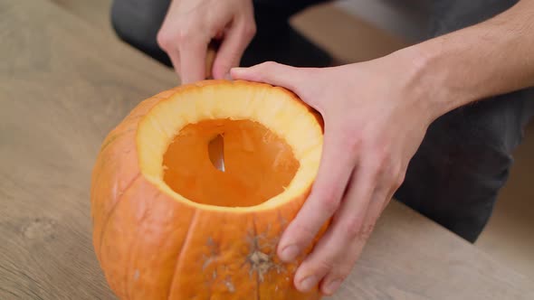 Young Man Cuts Teeth in Jack Lantern with a Knife alt