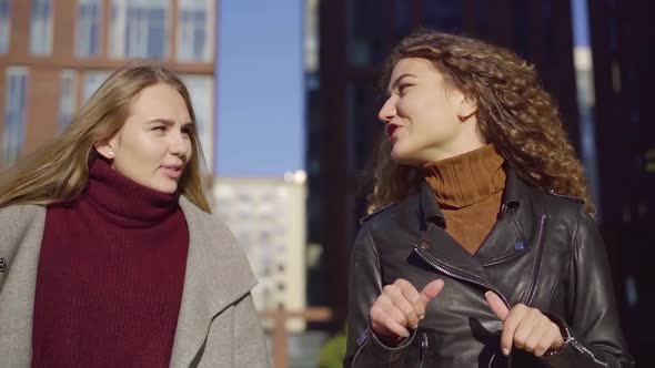 Happy Young Girl Friends Walk Around the City During the Day and Gossip alt