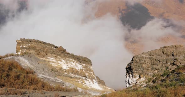 Stones and Grass on the Background of Which Clouds Covering the Mountains alt