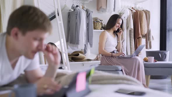 Lady with Laptop Talks on Phone While Man Uses Tablet