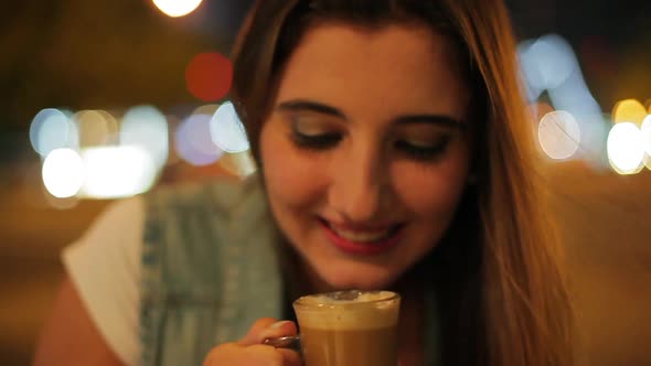 Teenage girl drinking coffee outdoors at night