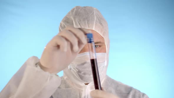 Man in Protective Suit Medical Mask Gloves Shows Test Tube with Coronovirus