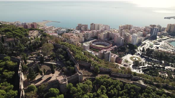 Fly over Castillo de Gibralfaro fortress and reveal of Plaza de Toros La Malagueta bullring, Malaga,