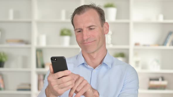 Portrait of Focused Middle Aged Businessman Using Smartphone  alt