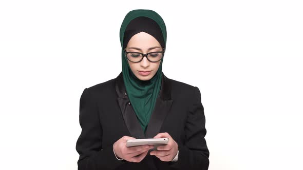 Portrait of Smart Arabic Woman in Headscarf Typing Text Messages or Browsing on Digital Tablet alt