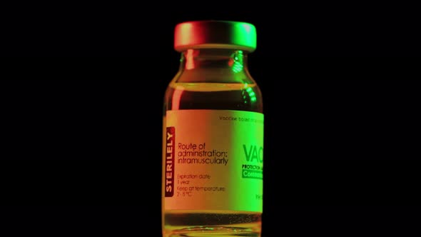 Flacon of Vaccine for Coronavirus COVID19 Cure are Slowly Spinning Under Red and Green Light alt