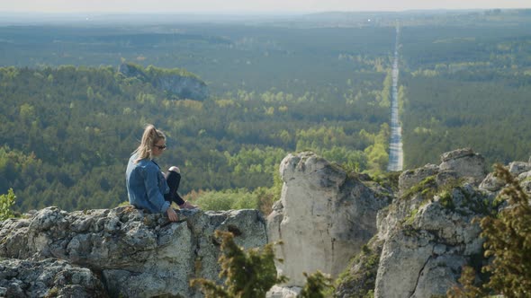 Woman Sitting On A Rocky Hilltop