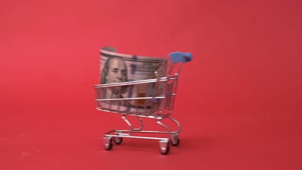 Shopping Cart with One Hundred Dollar Banknote on Red Background Buying Currency