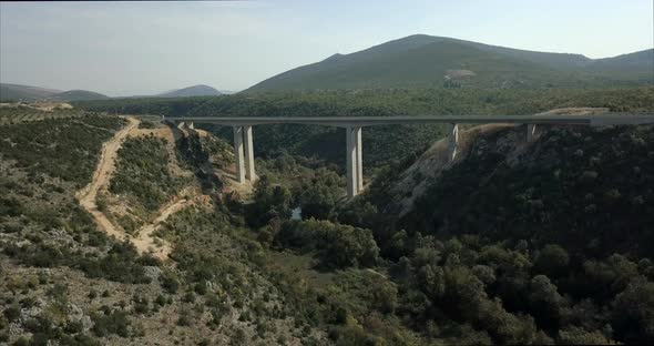 Wide aerial shot of a bridge in Bosnia and Herzegovina. the camera rises up to show the bridge alt