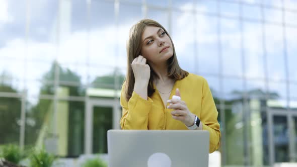 Woman Wearing Earphones Looking at Laptop Computer While Sitting at Outdoor