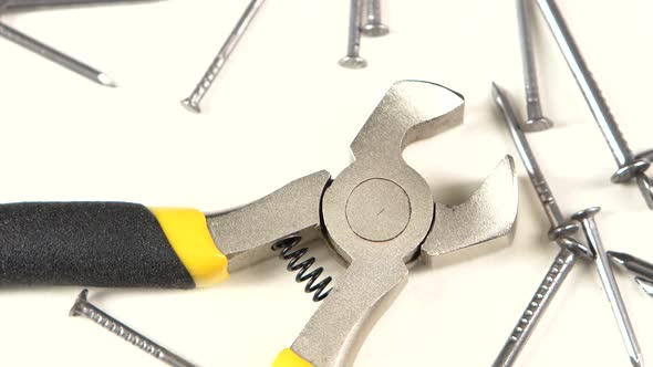 Wire Cutters with Yellow, Gray Handle on White Among Nails, Rotation, Close Up alt