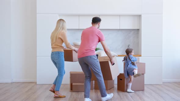 Amazed family parents and little funny daughter bring brown cardboard boxes alt