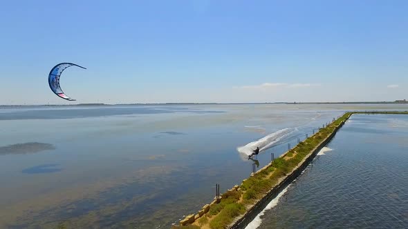 Aerial drone view of a man kiteboarding on a kite board. alt