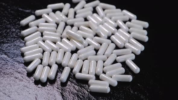 White Capsules or Tablets Rotating on a Black Background