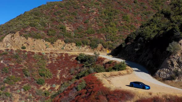 Panning left aerial shot of a blue Tesla Model S on Mt. Baldy in Southern California. alt