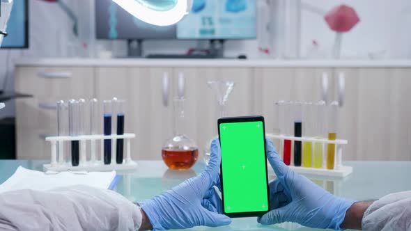 Scientist Holds a Smarphone with Isolated Green Screen Mock-up alt