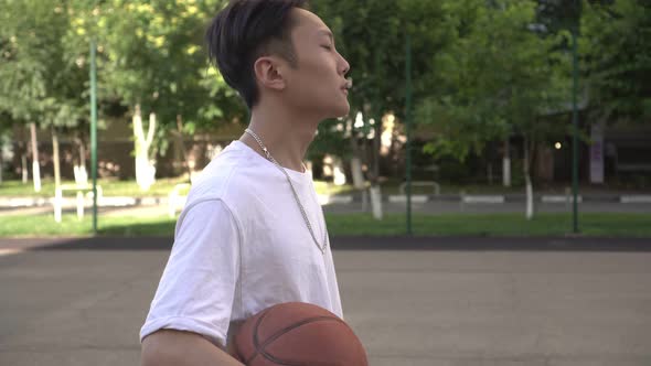 Young Asian Sporty Man with a Basketball Outdoors alt