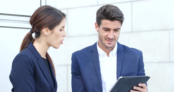 Business people discuss on tablet computer alt