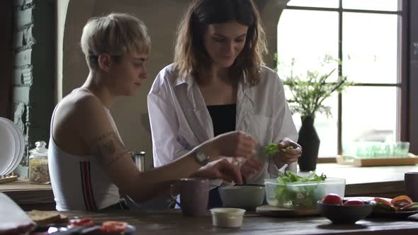 Happy Homosexual Couple Is Making Vegetable Salad and Talking at Table in Kitchen. Spbd alt