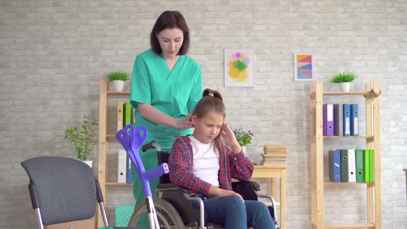 Doctor Masseur Doing Neck Massage To a Teenage Girl in a Wheelchair alt