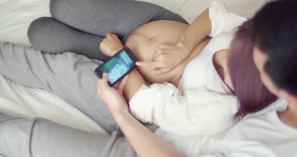 Caucasian husband with a pregnant wife looking ultrasound photo of her newborn baby.