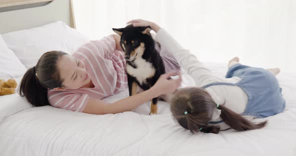 Mother and daughter playing with black dog on bed (3)