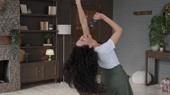 Young Attractive Active Woman Funny Dances Dynamic in Modern Living Room Listens to Music Sings alt
