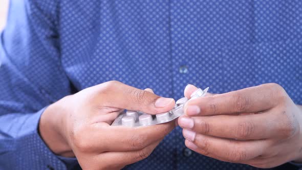 Close Up of Man's Hand Taking Pills From a Blister Pack alt