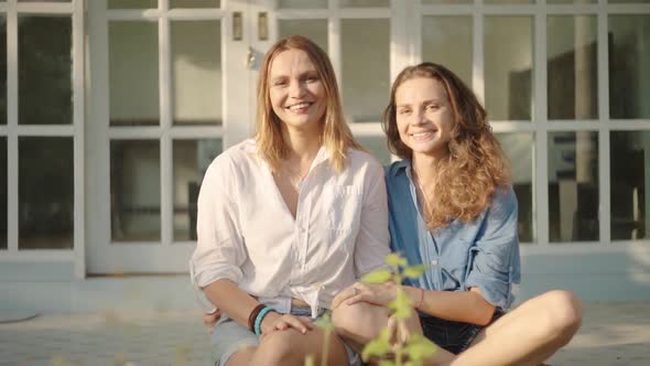 Happy Lesbian Couple Sitting on the Porch of Their House alt